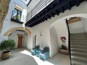 a hallway with two blue chairs and a staircase at CAMASanlúcar in Sanlúcar de Barrameda