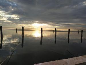 a sunset on the water with poles in the water at La casa di Alice in Venice