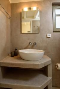 La salle de bains est pourvue d'un lavabo blanc et d'un miroir. dans l'établissement Araklos II, à Aegiali
