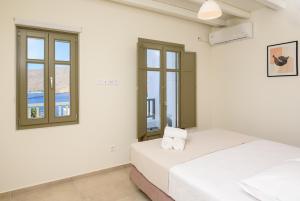 2 camas en una habitación blanca con ventanas en Araklos II, en Egíali