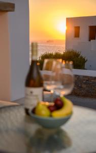 una botella de vino y un bol de fruta en una mesa en Araklos II, en Egíali