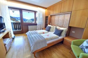 ein Schlafzimmer mit einem Bett und einem großen Fenster in der Unterkunft Apartment Nogler Frieda in Wolkenstein in Gröden