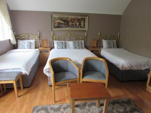 two beds in a room with two chairs and a table at Dungimmon House in Ballyconnell