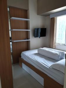 a bedroom with a bed and a tv on the wall at Cosmy Tanglin Apartment in Surabaya