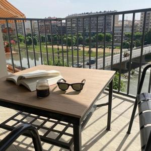 una mesa con gafas y un libro en el balcón en Apartamento completamente reformado en el casco antiguo con vistas al rio, en Balaguer