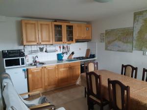 eine Küche mit Holzschränken, einem Tisch und einer Spüle in der Unterkunft Apartmán u Benkov in Lúčky