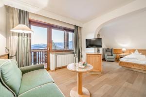a hotel room with a bed and a couch and a table at Royal Hotel Hinterhuber in Brunico +107 photos