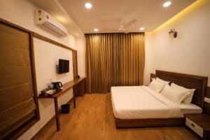 a hotel room with a bed and a television at Pakoid Cottages in Idukki