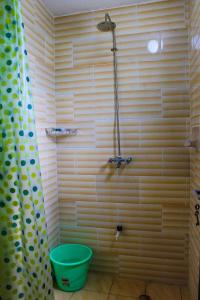 a bathroom with a shower with a bucket in it at Armaan Guest House in Diani Beach