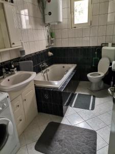 ein Badezimmer mit einer Badewanne, einem WC und einem Waschbecken in der Unterkunft Garden- pool apartman 