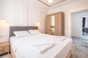 a white bedroom with a large bed with white sheets at Golden Rose Suit pension in Kaş