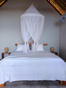sypialnia z białym łóżkiem z baldachimem w obiekcie Cassabonelly w mieście Maumere