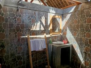 Baño de piedra con lavabo y espejo en Cassabonelly, en Maumere