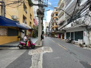 a person riding a scooter on a city street at Collection O Thaiphiphat House Silom in Bangkok