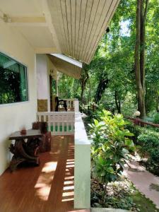 a porch of a house with a table and trees at Saiyok River House in Sai Yok