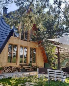 Pine Cabins Zlatibor في زلاتيبور: منزل خشبي أمامه شرفة ومقاعد