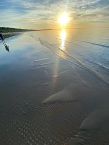 una spiaggia con il sole che sorge sull'acqua di BLUE SKY APARTMENT a Jūrmala