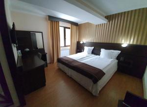 Habitación de hotel con cama grande y TV en Family Hotel Hebar, en Batak