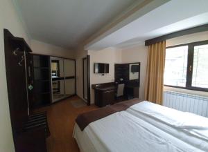 Schlafzimmer mit einem Bett, einem Schreibtisch und einem Fenster in der Unterkunft Family Hotel Hebar in Batak