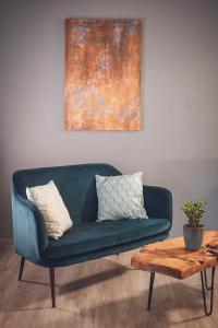 eine blaue Couch in einem Wohnzimmer neben einem Tisch in der Unterkunft Hotel Villa Alberta in Nago-Torbole