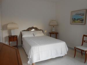 a bedroom with a white bed and a chair at Chez Mamouska in Cassis