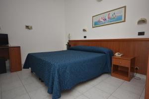 a bedroom with a bed with a blue comforter at Hotel Eden in Bellaria-Igea Marina