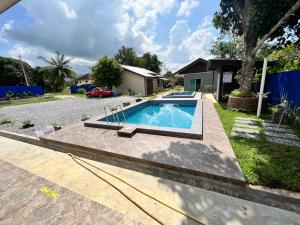 a swimming pool in front of a house at Tok Abu Heritage Roomstay in Pantai Cenang