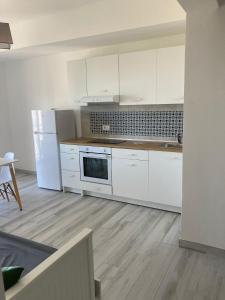 cocina con electrodomésticos blancos y suelo de madera en KROTONIATI APARTMENT, en Crotone