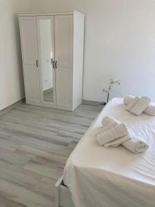 um quarto com uma cama branca e toalhas em KROTONIATI APARTMENT em Crotone