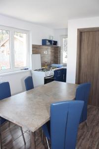 cocina con mesa de madera y sillas azules en Casa Korina, en Azuga