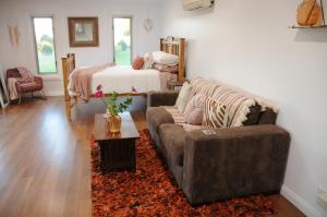 a living room with a couch and a bed at Wagtail Nest Country Retreat - Longford Vic 3851 in Sale +5 photos
