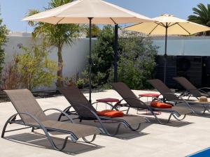 a group of chairs and umbrellas next to a pool at Casa Alice in Playa Blanca