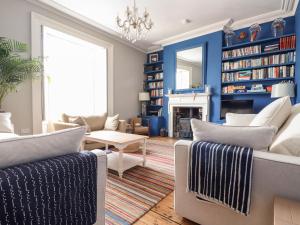 a living room with blue walls and white furniture at The Water House in Falmouth