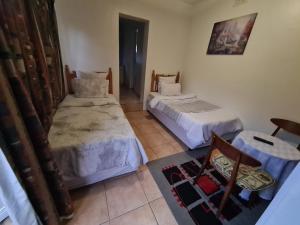 a room with two beds and a chair in it at Zenith House Boston Self Catering Accomodation in Cape Town