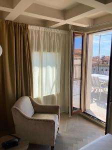 a living room with a chair and a balcony at Hotel Dei Dragomanni in Venice