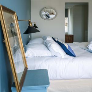 een slaapkamer met een wit bed en een spiegel bij La Maison du Vieux Port in Flamanville