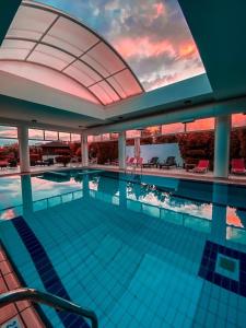 a large swimming pool with a sunset in the background at Kalloni Luxury Apartment in Volos