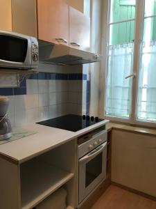 a kitchen with a stove top oven next to a microwave at Les Platanes - Gaugain in Lamalou-les-Bains