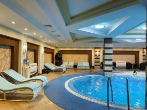 a pool in a hotel lobby with chairs and a swimming pool at Samal Resort & SPA in Almaty