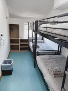 a room with two bunk beds and a blue floor at Voyage Hostel - Rooms with Shared Kitchen in Douglas