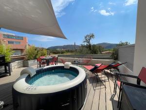 a hot tub on a deck with chairs and tables at Superbe appartement sur le port, jacuzzi, piscine in Porto-Vecchio