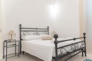 1 dormitorio con cama de metal con sábanas y almohadas blancas en Il vecchio arco en Novoli
