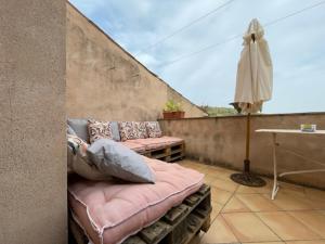 uma varanda com um sofá, um guarda-chuva e uma mesa em Appartement Le Grenadier em Cotignac