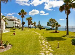 a walkway through a park with palm trees and the ocean at My Space on the Beach, Luxury Apartment in Casares