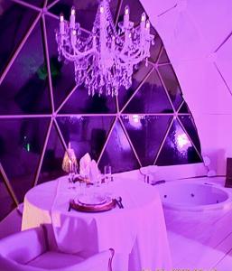 Habitación púrpura con mesa y lámpara de araña. en Domo Suites Masía Cal Geperut en Badalona