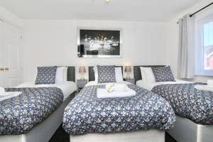 a room with four beds with pillows at Tranquil 4Bed Retreat - 3 Min to M6, 10 Min to Coventry City Centre in Coventry