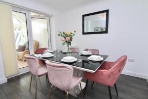 ein Esszimmer mit einem schwarzen Tisch und rosa Stühlen in der Unterkunft Tranquil 4Bed Retreat - 3 Min to M6, 10 Min to Coventry City Centre in Coventry