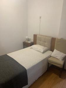 a bedroom with a large bed and a chair at Residencial Encontro in Vila Real