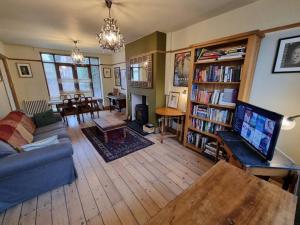 ein Wohnzimmer mit einem Sofa, einem Tisch und einem TV in der Unterkunft 3-bedroom house in Chorlton full of character in Manchester