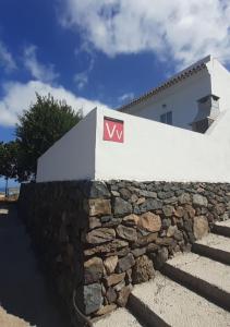 Una pared de piedra con un cartel encima. en Vv Puerto del Trigo - Sirena, en Alojera